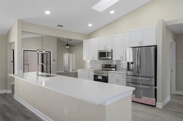 a kitchen with stainless steel appliances white cabinets and a stove a refrigerator with wooden floor