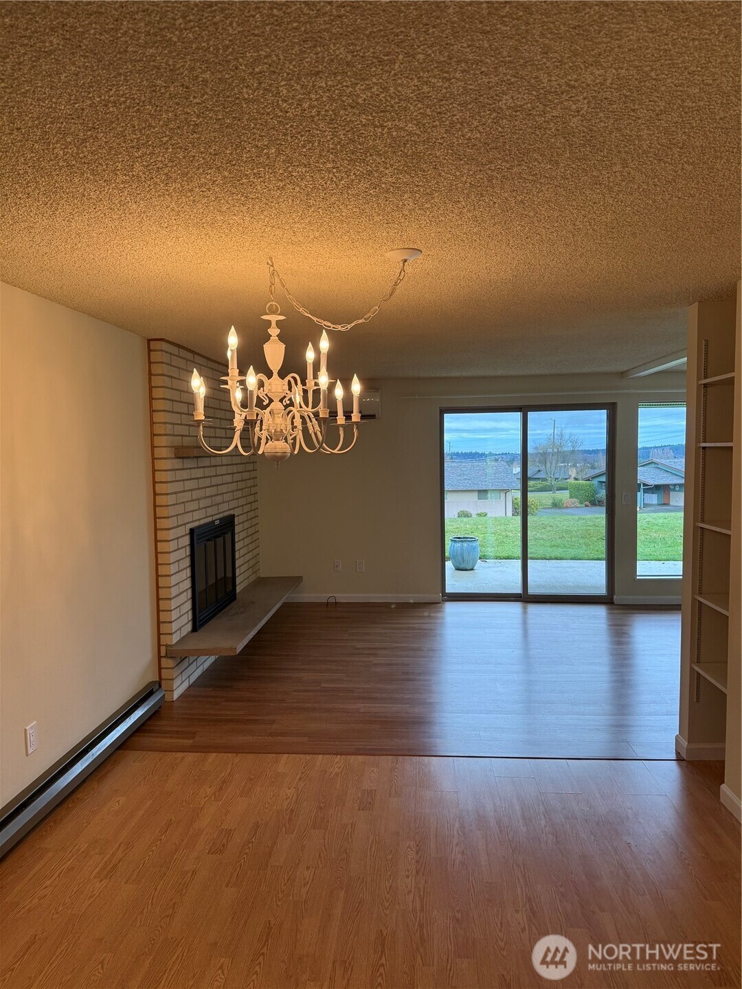 1301 South 3rd Avenue, Unit 5B Sequim, WA 98382 - Photo 11 of 24 an empty room with wooden floor fireplace and chandelier