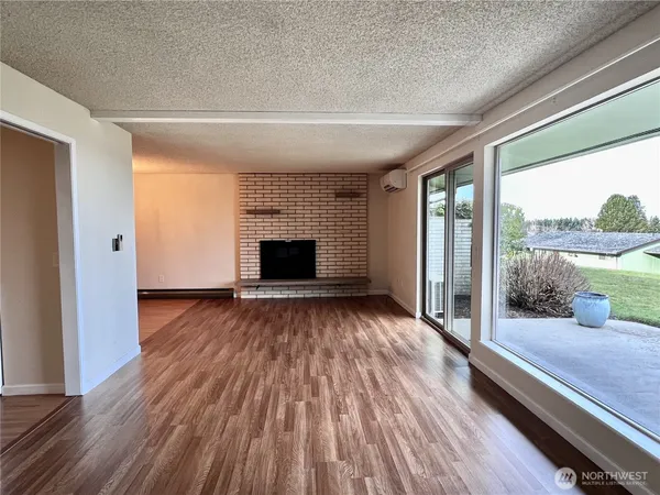 a view of empty room with wooden floor and fireplace