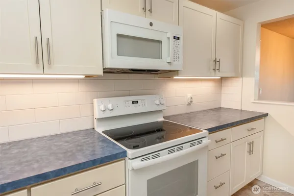 a kitchen with granite countertop white cabinets and white appliances