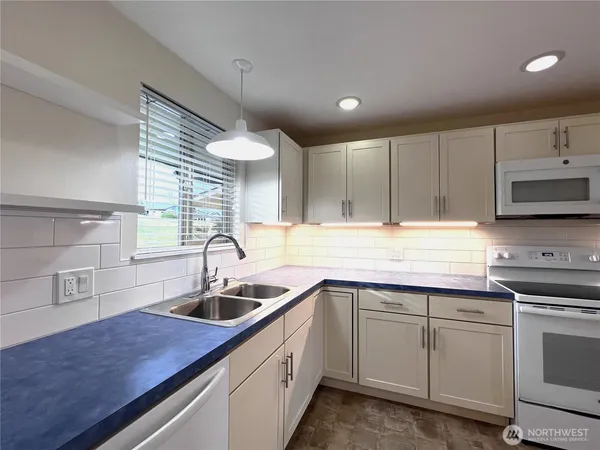 a kitchen with kitchen island white cabinets appliances and a sink