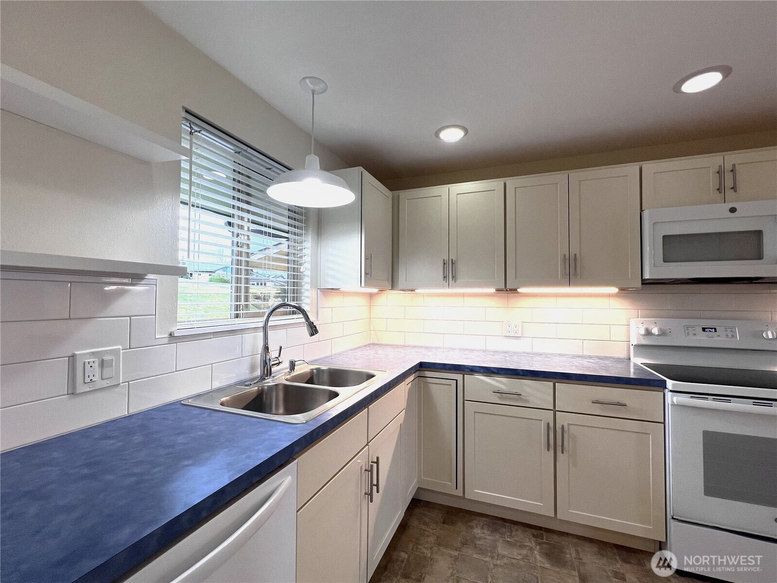 1301 South 3rd Avenue, Unit 5B Sequim, WA 98382 - Photo 7 of 24 a kitchen with kitchen island white cabinets appliances and a sink