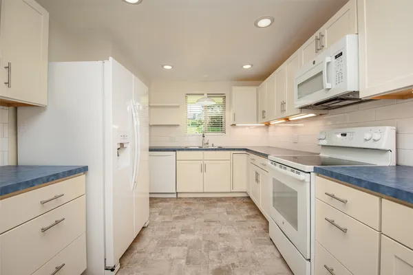 a kitchen with granite countertop white cabinets and white appliances