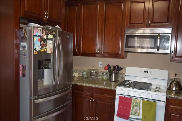 a kitchen with stainless steel appliances granite countertop a refrigerator and a stove top oven