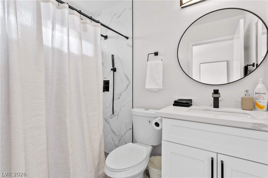 101 Beaver Ridge Avenue North Las Vegas, NV 89031 - Photo 16 of 42 A pristine bathroom featuring modern fixtures and a spacious vanity with an elegant circular mirror.