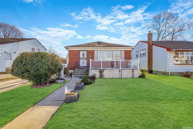 a view of a house with a big yard plants and large tree