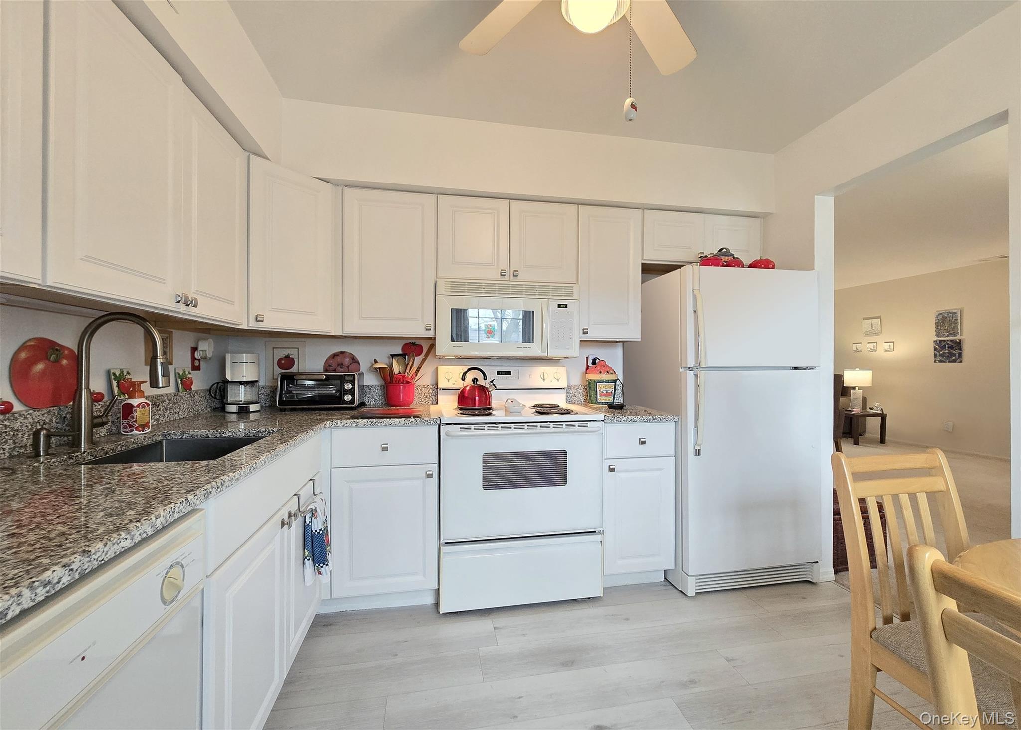 655 Middle Country Road, Unit 22E2 Coram, NY 11727 - Photo 6 of 16 a kitchen with refrigerator a stove a sink dishwasher and a refrigerator with white cabinets