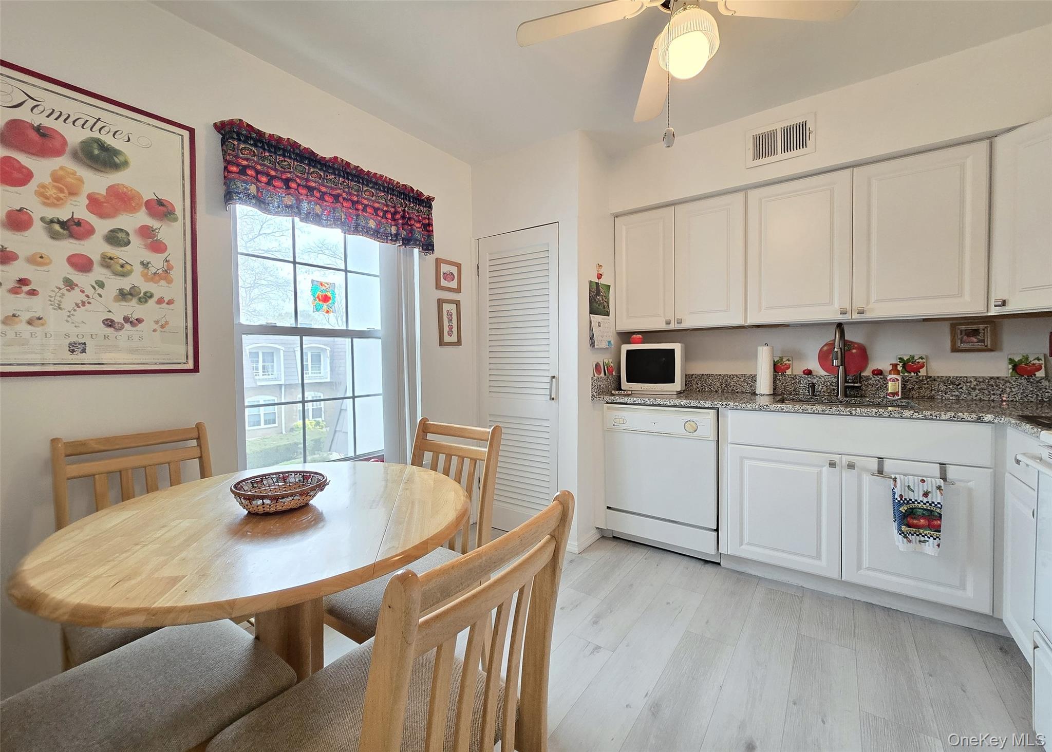 655 Middle Country Road, Unit 22E2 Coram, NY 11727 - Photo 7 of 16 a kitchen with stainless steel appliances granite countertop a sink a microwave a dining table and chairs with wooden floor