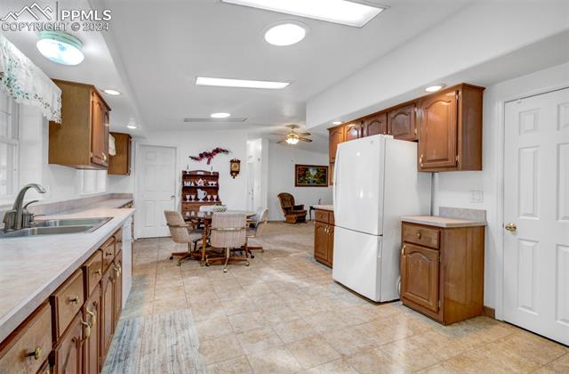 12825 Garrett Road Peyton, CO 80831 - Photo 18 of 47 Kitchen featuring ceiling fan, white refrigerator, sink, and light tile patterned floors