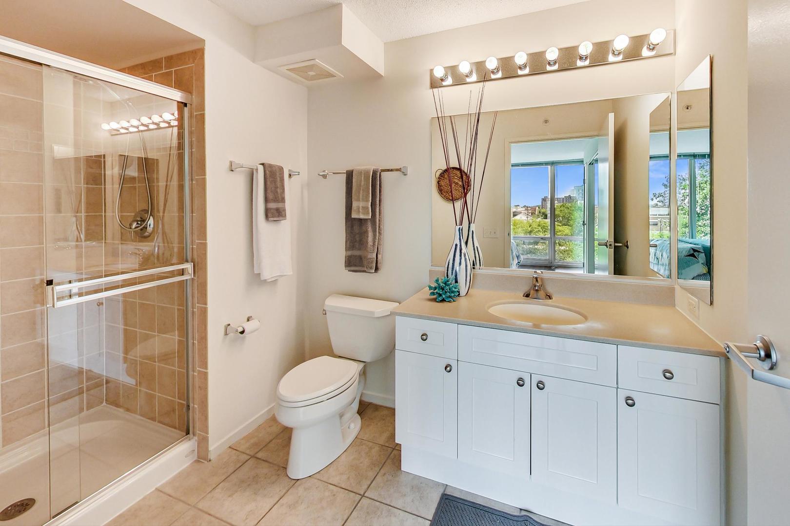 800 Elgin Road, Unit 702 Evanston, IL 60201 - Photo 11 of 16 a spacious bathroom with a shower sink and mirror