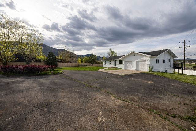 4155 Johnson Road Nibley, UT 84321 - Photo 55 of 71 View of side of home with driveway, board and batten siding, a mountain view, and an attached garage