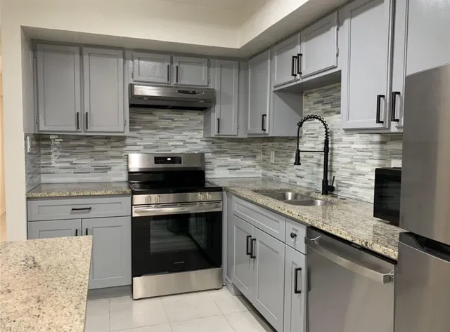 a kitchen with granite countertop a sink stainless steel appliances and cabinets