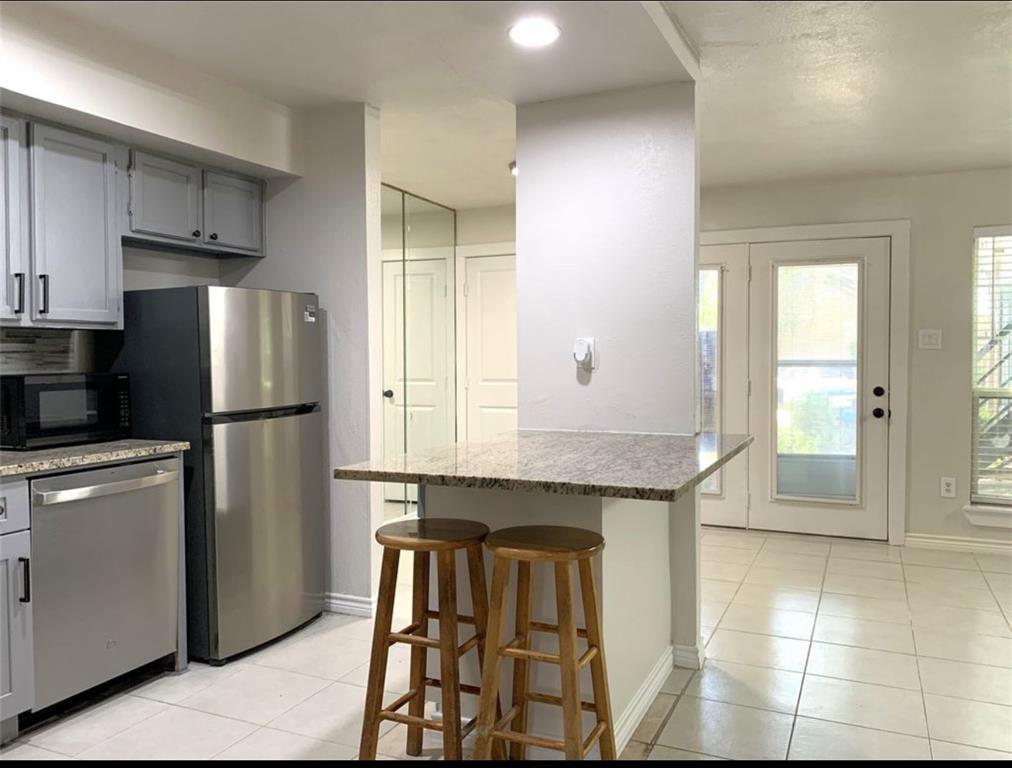 9803 Walnut Street, Unit 107 Dallas, TX 75243 - Photo 3 of 10 a kitchen with stainless steel appliances granite countertop a refrigerator and a stove