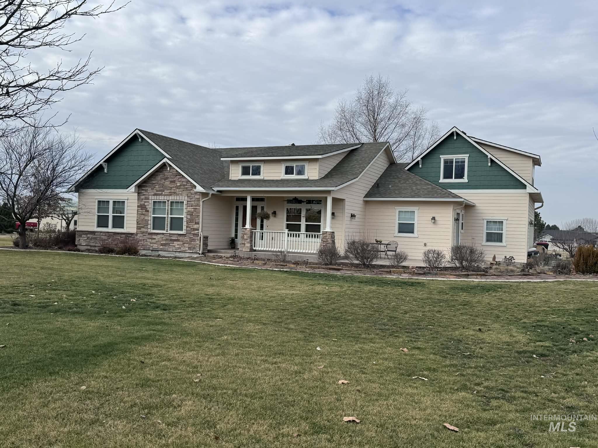 24331 Cowboy Lane Middleton, ID 83644 - Photo 2 of 5 Craftsman inspired home with a porch, a front yard, stone siding, and a shingled roof
