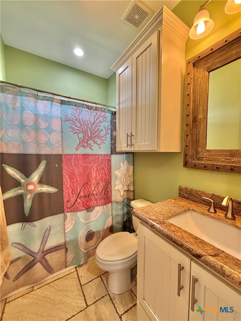 403 Maple Street Port O'Connor, TX 77982 - Photo 19 of 48 a bathroom with a granite countertop bathtub sink vanity mirror and toilet