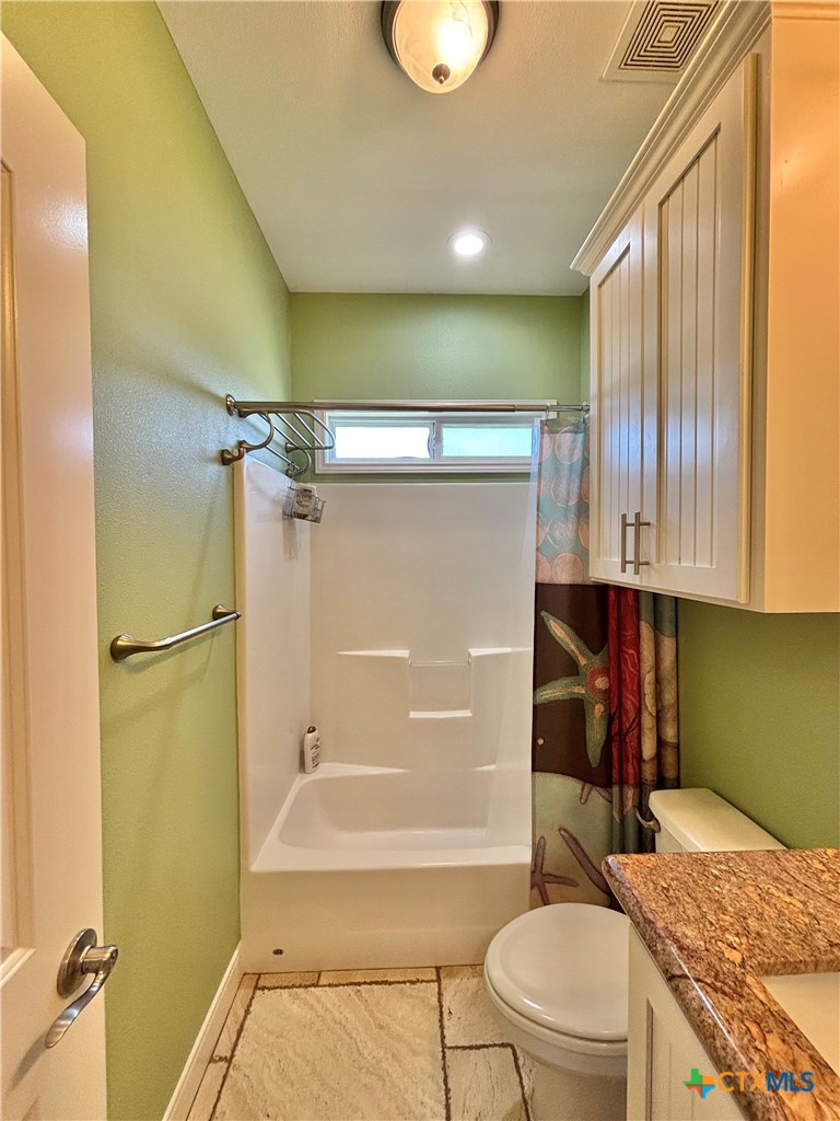 403 Maple Street Port O'Connor, TX 77982 - Photo 20 of 48 a bathroom with a granite countertop bathtub sink vanity mirror and toilet