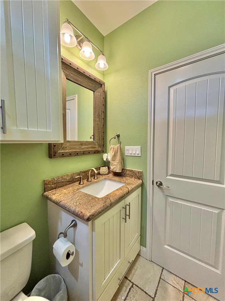403 Maple Street Port O'Connor, TX 77982 - Photo 21 of 48 a bathroom with a granite countertop sink and a mirror