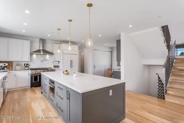 a large kitchen with kitchen island a stove a sink a refrigerator a center island and wooden floor