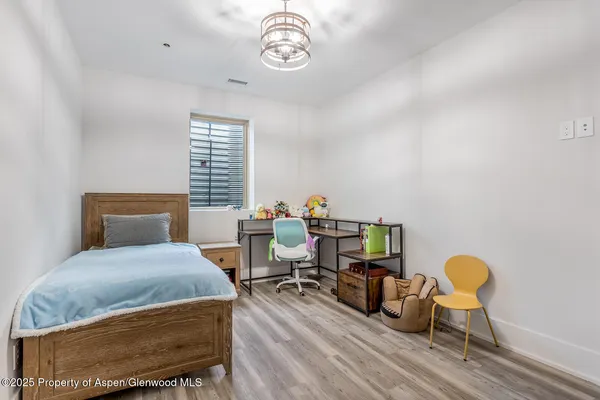 a bedroom with a bed chair and wooden floor