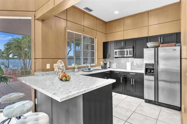 a kitchen with stainless steel appliances granite countertop a sink and a refrigerator