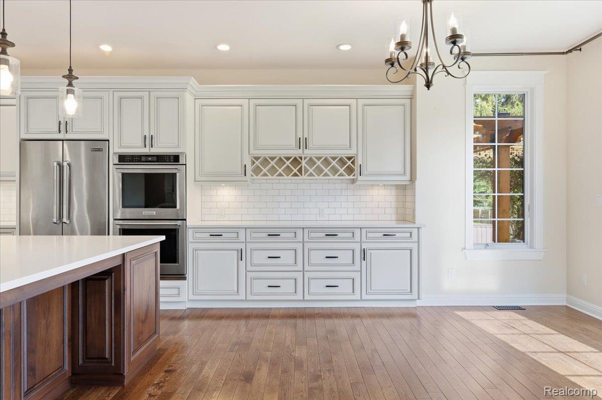 35339 West 13 Mile Road Farmington, MI 48331 - Photo 10 of 72 Kitchen with stainless steel appliances, backsplash, hardwood flooring, two tone color scheme, and a chandelier