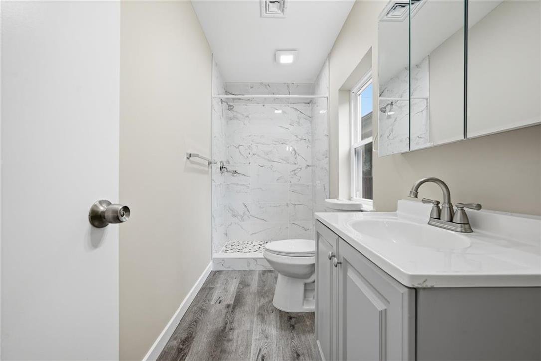 5641 North Coplay Road Whitehall, PA 18052 - Photo 19 of 68 A well-appointed bathroom features a marble-tiled shower, stylish vanity, and warm wood flooring.