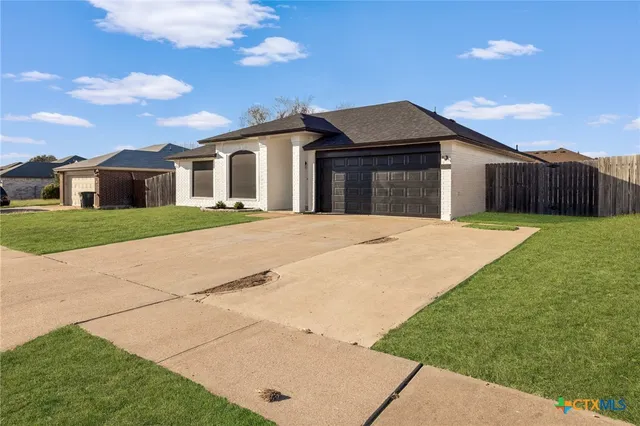 a white house with a yard and a large tree