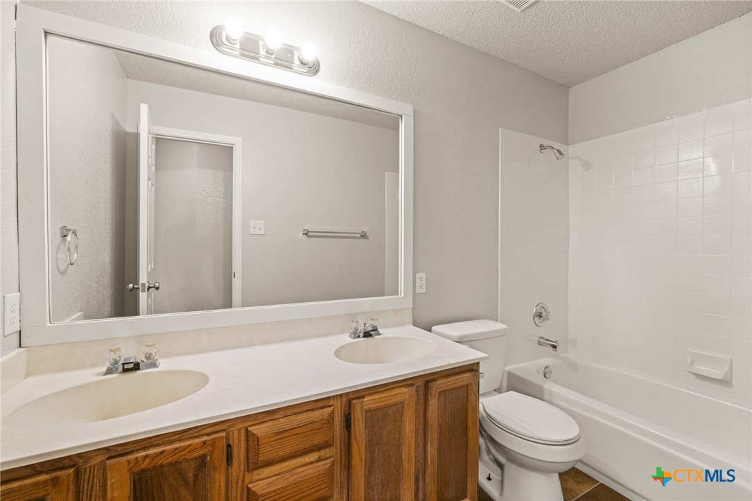 4215 Rifle Drive Killeen, TX 76542 - Photo 22 of 30 a bathroom with a granite countertop sink toilet mirror and bathtub