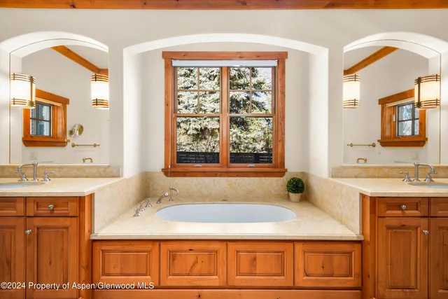 a bathroom with a granite countertop tub sink and mirror