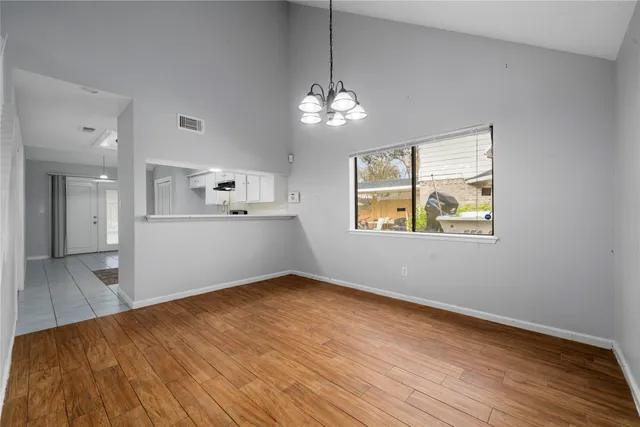 a view of a room with wooden floor chandelier and windows