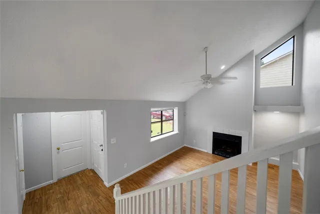 a view of an empty room with wooden floor and windows