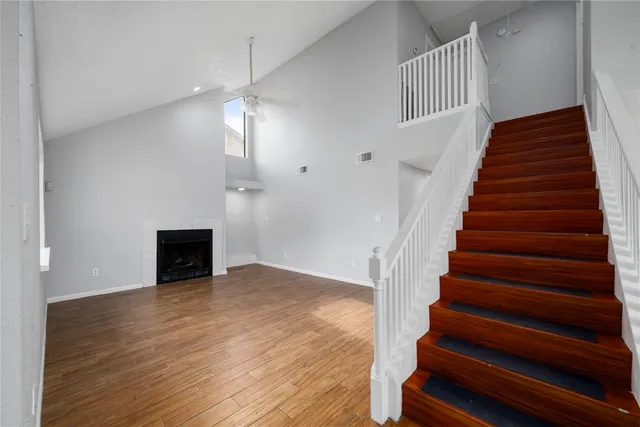 a view of an empty room with wooden floor a ceiling fan and windows