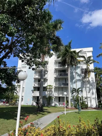 a front view of a building with streets and trees