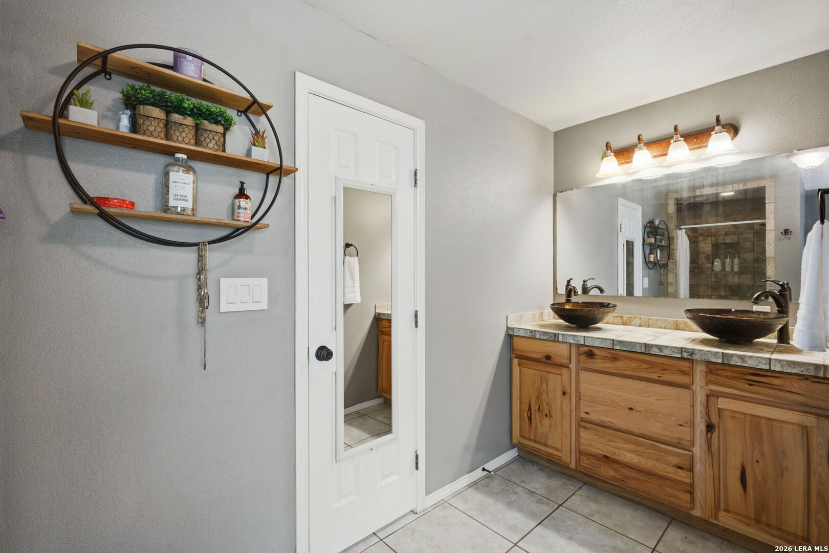 202 Bryan Drive Jourdanton, TX 78026 - Photo 22 of 28 a bathroom with a sink a mirror a vanity and shower view
