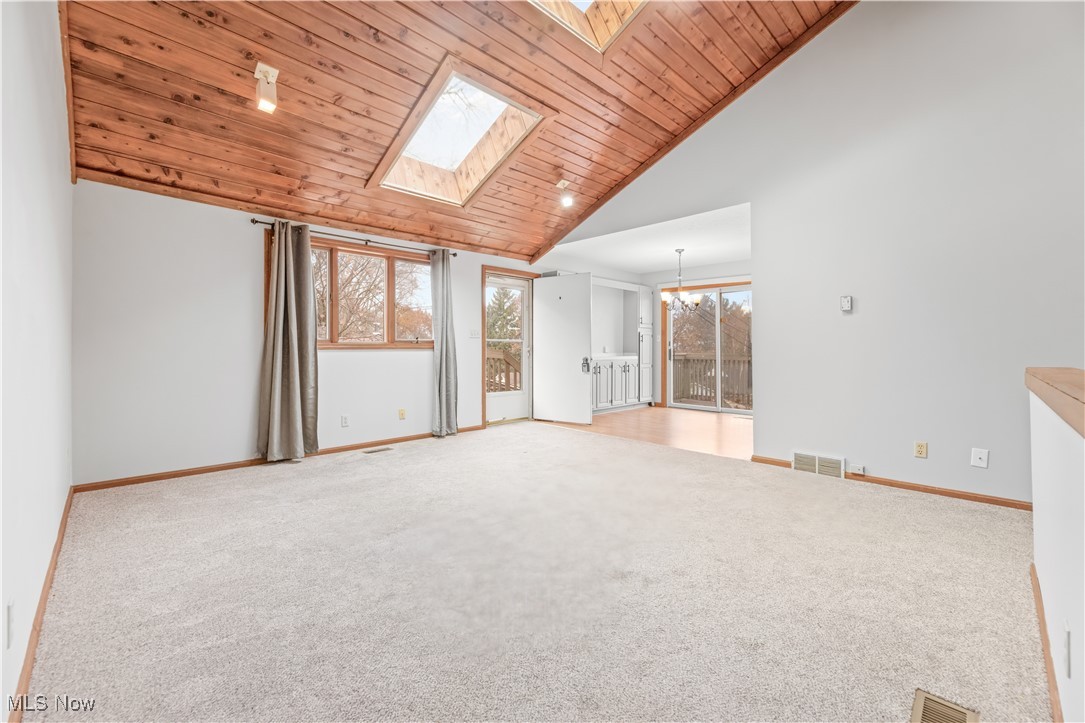 1574 Faye Road Akron, OH 44306 - Photo 6 of 45 Carpeted empty room featuring a chandelier, wood ceiling, high vaulted ceiling, and a skylight