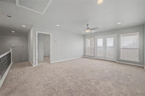 an empty room with chandelier fan and windows