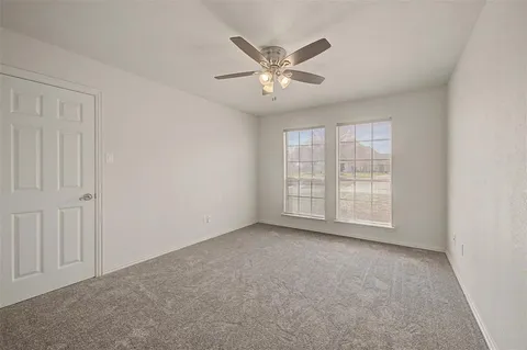 an empty room with chandelier fan and windows
