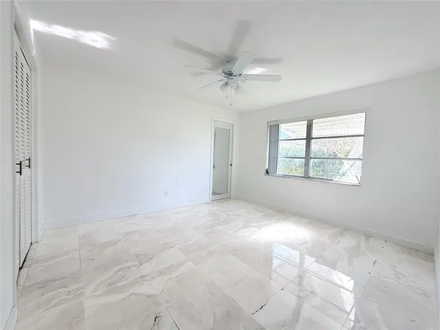 an empty room with windows and fan