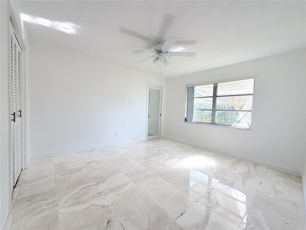 340 Northwest 25th Court Pompano Beach, FL 33064 - Photo 13 of 17 an empty room with windows and fan