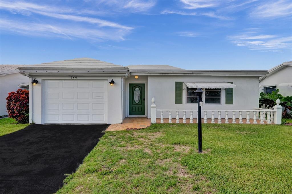 340 Northwest 25th Court Pompano Beach, FL 33064 - Photo 2 of 17 a front view of a house with a yard and garage