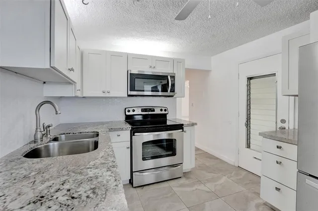 a kitchen with stainless steel appliances granite countertop a stove a sink and a microwave