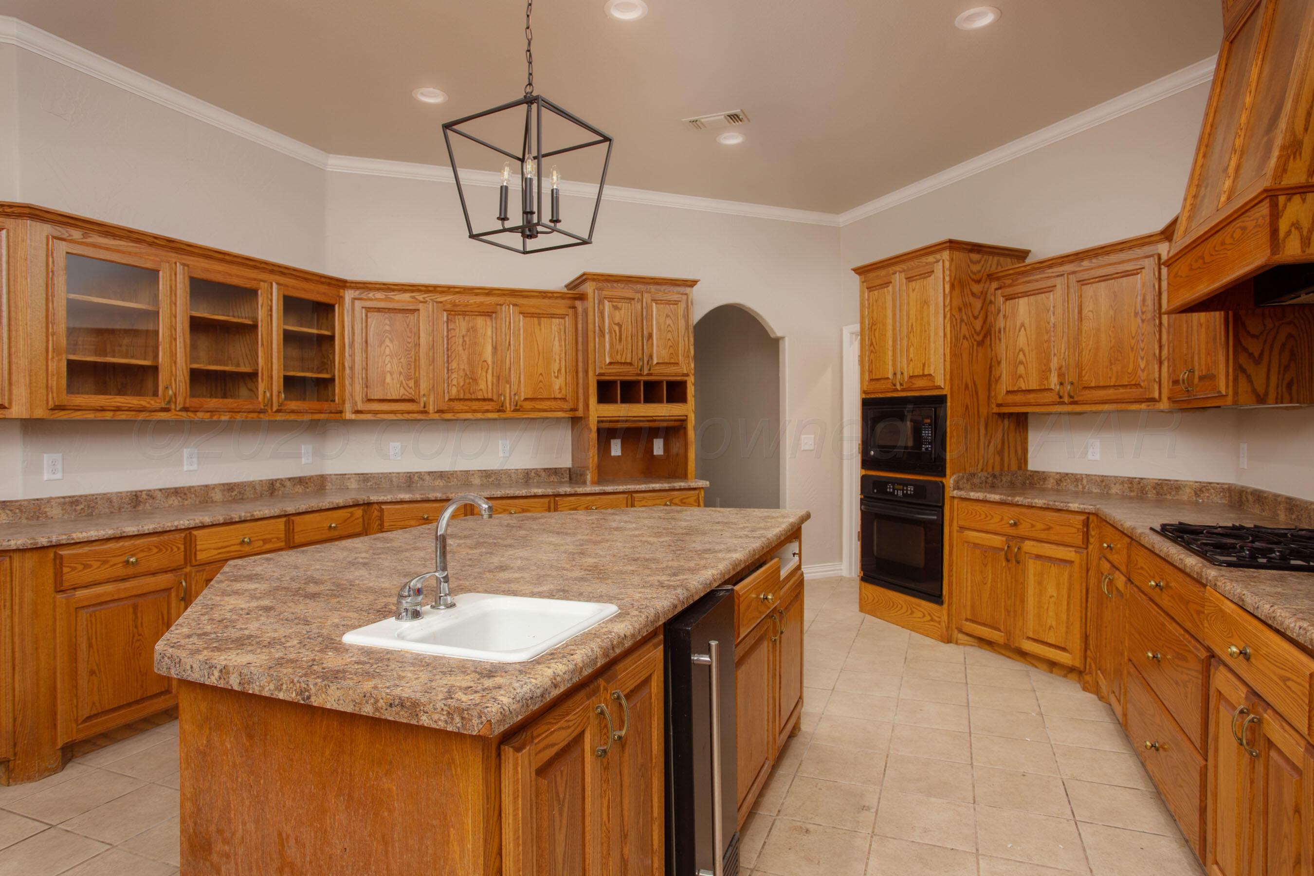 9050 Greyhawk Road Amarillo, TX 79119 - Photo 7 of 55 a kitchen with stainless steel appliances granite countertop a sink counter space cabinets and wooden floor