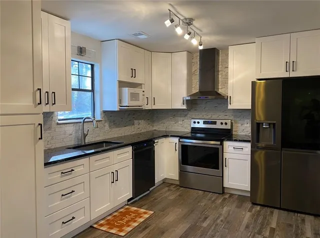 a kitchen with granite countertop white cabinets and stainless steel appliances