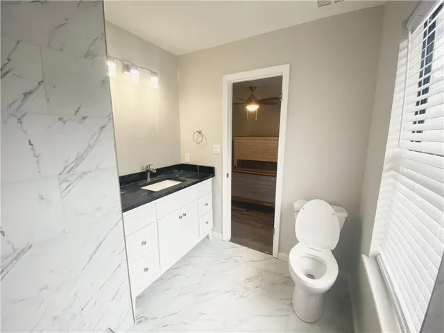 a bathroom with a granite countertop toilet and a sink
