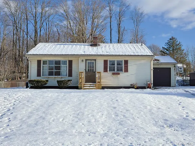 a front view of house with yard and trees in the background