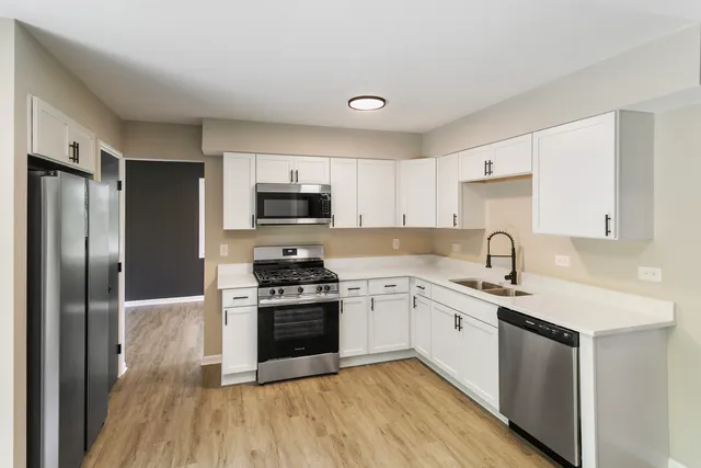 a kitchen with stainless steel appliances granite countertop a stove top oven a sink and a refrigerator