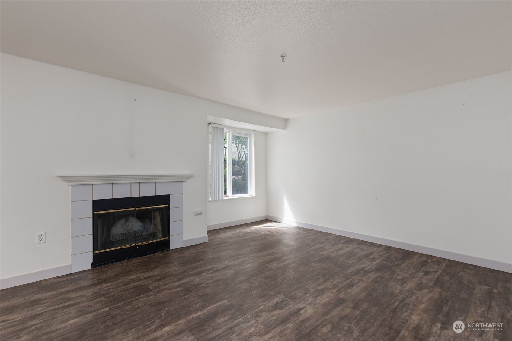11002 Southeast Petrovitsky Road, Unit E101 Renton, WA 98055 - Photo 6 of 40 a view of an empty room with wooden floor fireplace and a window