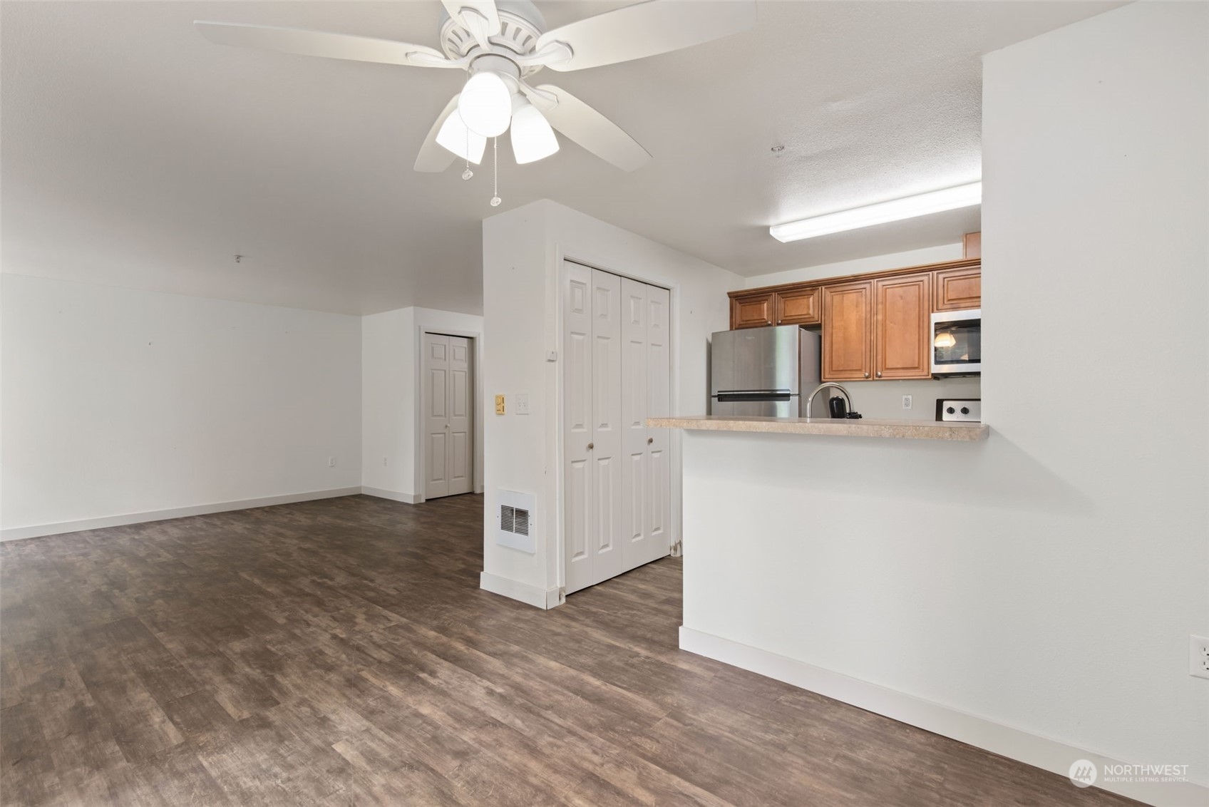 11002 Southeast Petrovitsky Road, Unit E101 Renton, WA 98055 - Photo 9 of 40 a view of a kitchen with an empty space and a ceiling fan