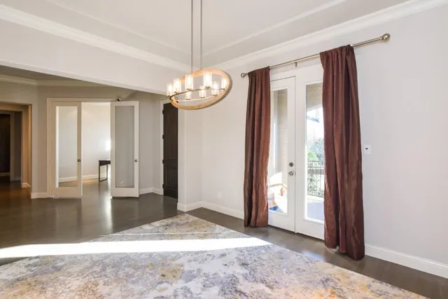 an empty room with chandelier fan and windows