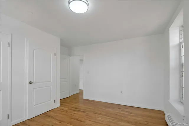 a view of an empty room with wooden floor and closet